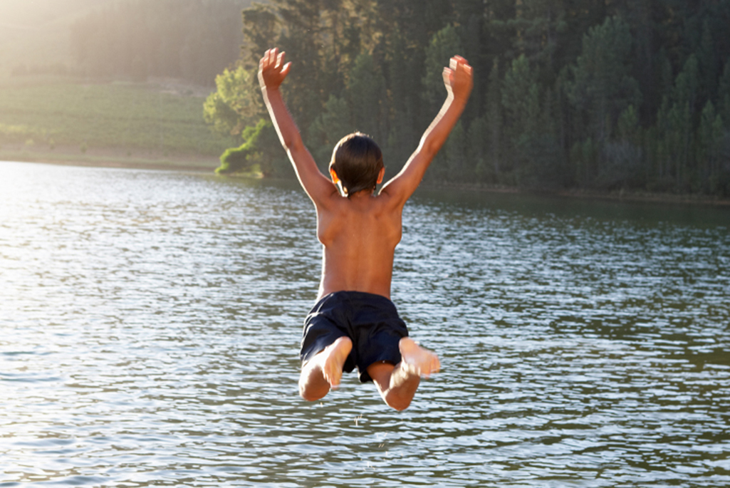 Foto på en ung kille som hoppar ner i vattnet.